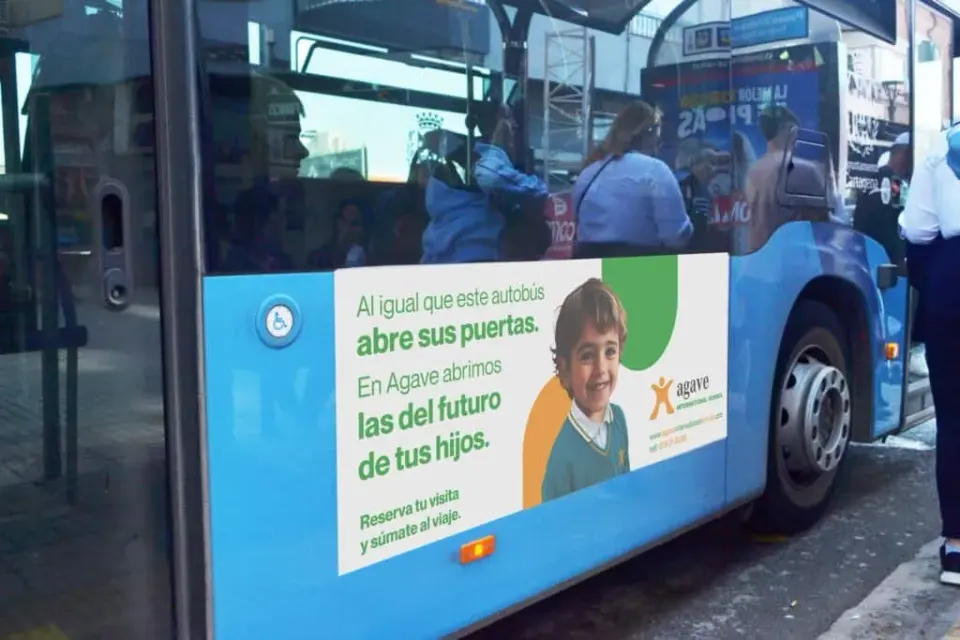 Puerta de autobús con cartel de campaña escolar Agave International School en la ciudad.